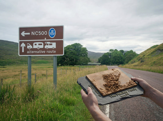 NC500 terrain block held up next to the NC500 road sign in the Highlands